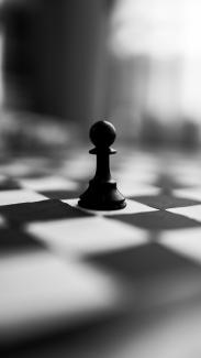 black chess piece on white and black checkered textile by Dipesh Shrestha courtesy of Unsplash.