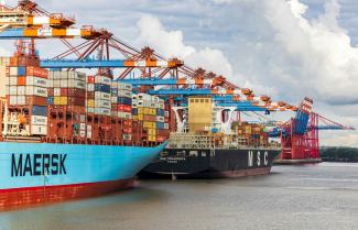 blue and red cargo ship on dock during daytime by Dominik Lückmann courtesy of Unsplash.