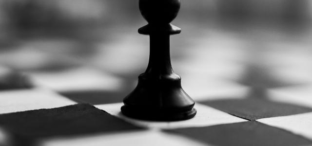 black chess piece on white and black checkered textile by Dipesh Shrestha courtesy of Unsplash.