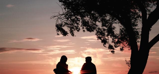 silhouette of two person sitting on chair near tree by Harli  Marten courtesy of Unsplash.