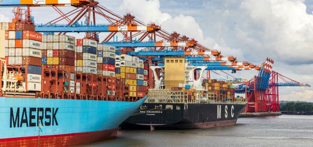 blue and red cargo ship on dock during daytime by Dominik Lückmann courtesy of Unsplash.